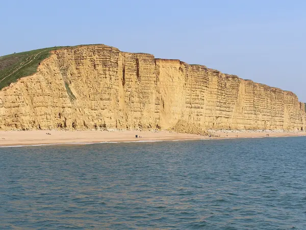 Golden sandstone East Cliff rising above the beach at West Bay, Bridport