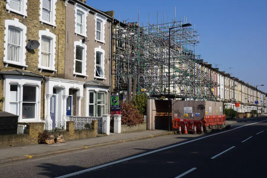 Scaffolding put up along a row of tall Victorian terraced houses for roof work