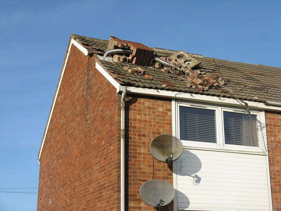 Gable end of a brick house where a storm brought down the chimney and smashed the roof tiles