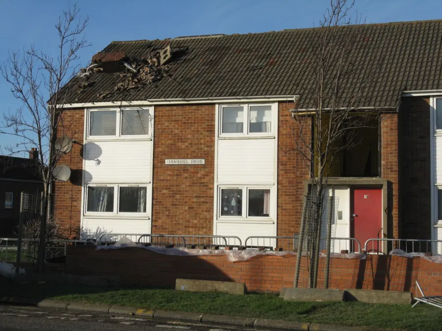 Storm damage to the tiled roof of a block of flats, clearly visible from the street
