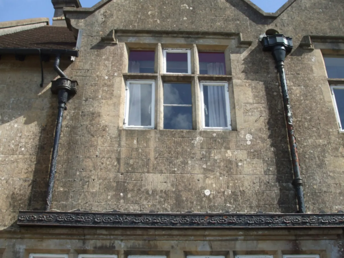 Black cast iron gutter, rainwater hoppers and downpipes on an old stone house