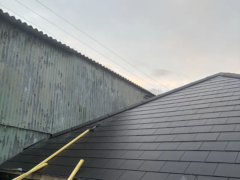 Completed slate roof on a single-storey outbuilding with a new timber gable