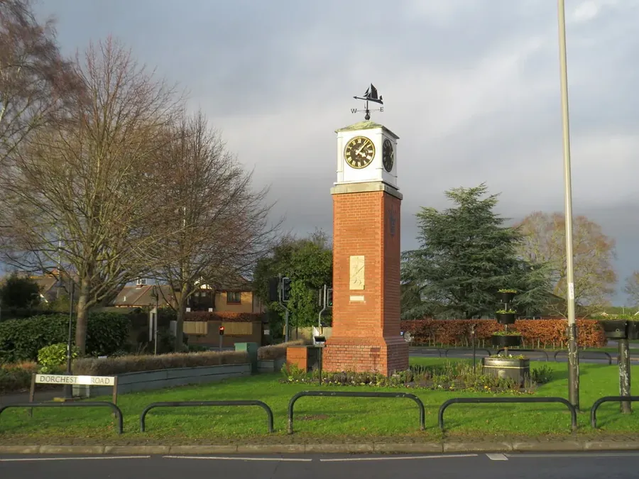 Brick clock tower at the centre of Upton, near Poole, with houses behind