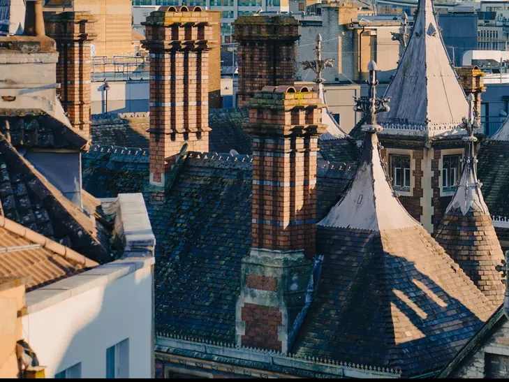 Banded Victorian brick chimney stacks and pointed slate turret roofs on an older town-centre roofline
